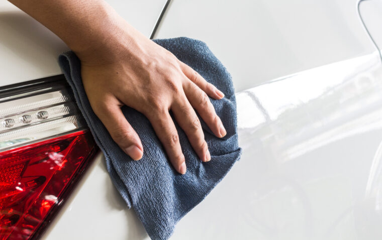 Hand with microfiber cloth polishing car